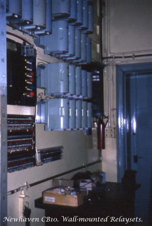 Photo:Wall-mounted relaysets in the Apparatus Room of Newhaven Manual Telephone Exchange. One was required for every outgoing junction to Brighton, Eastbourne, Lewes, Peacehaven and Seaford. There were many more out-of-picture. Nearer the camera is an alarm panel with different coloured bulbs, and beneath that, several rows of 'alarm-reporting' fuses that would cause a lamp on the alarm panel above to indicate the location of a blown fuse.