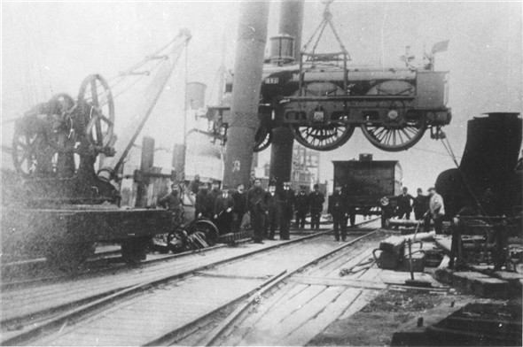 Photo:Sherlegs unloading a locomotive - c1900